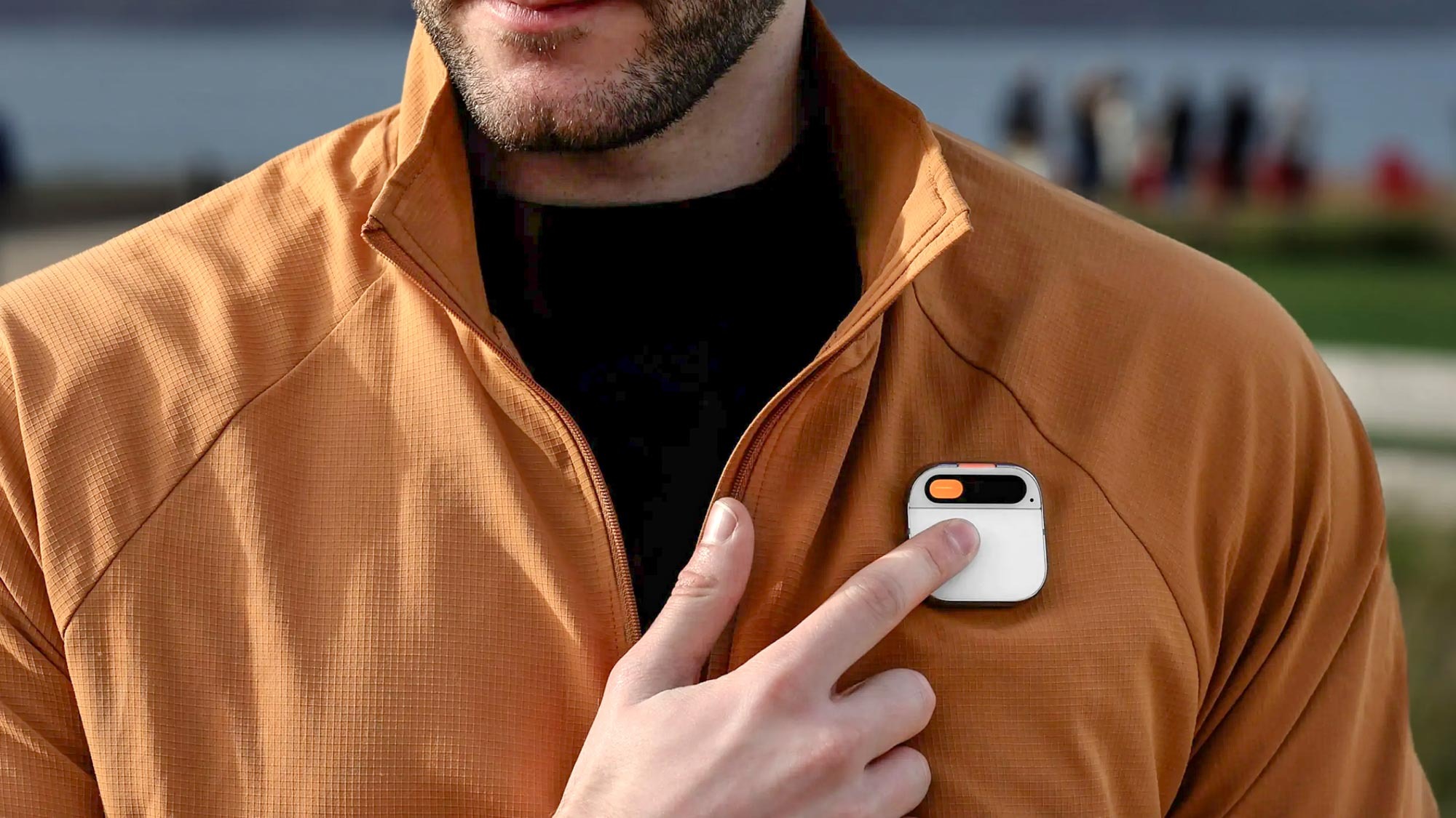 Une personne tapant sur le badge Humane AI porté sur sa veste