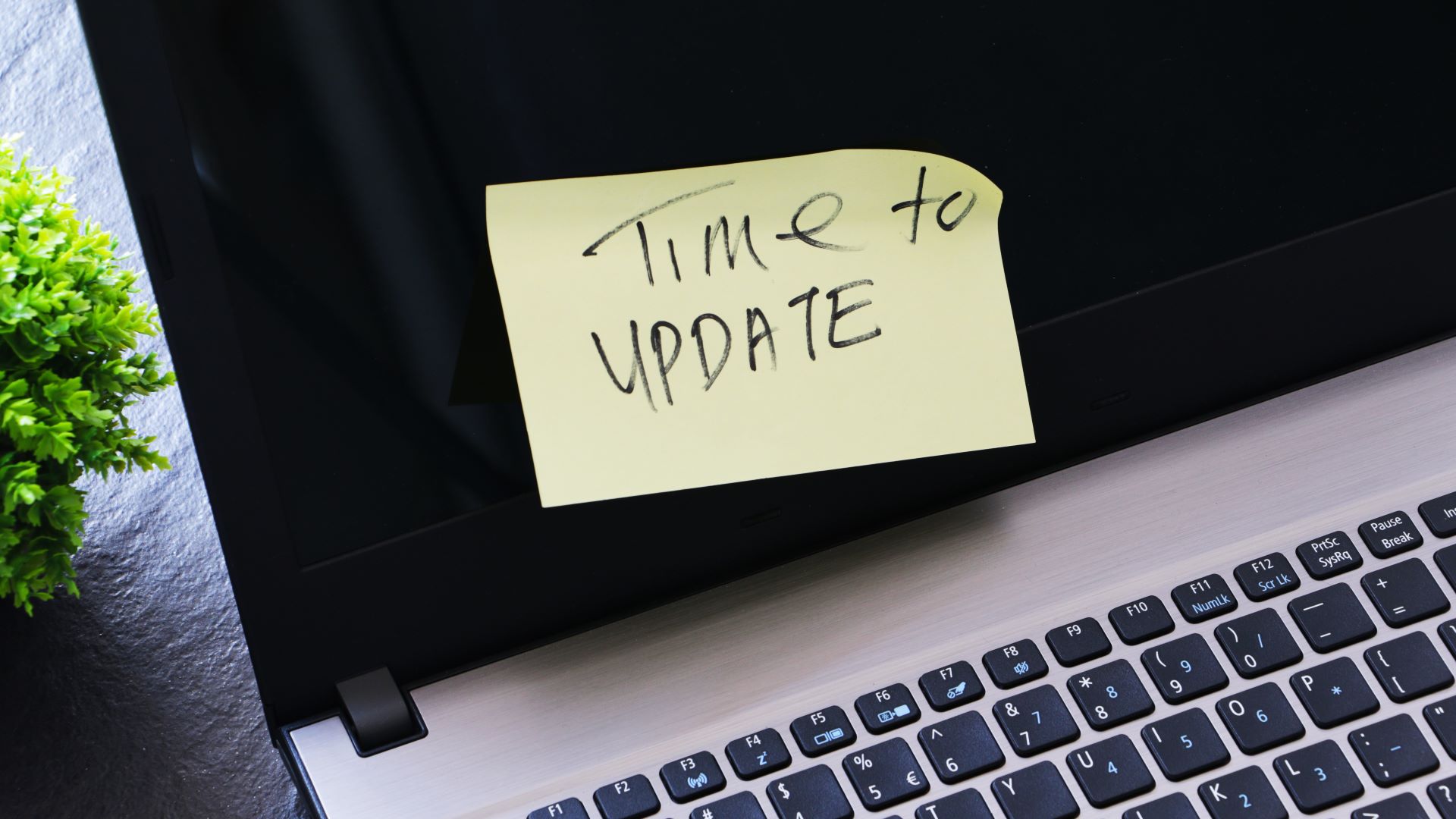 Un ordinateur portable avec un post-it jaune collé à l'écran sur lequel est écrit « Il est temps de mettre à jour »
