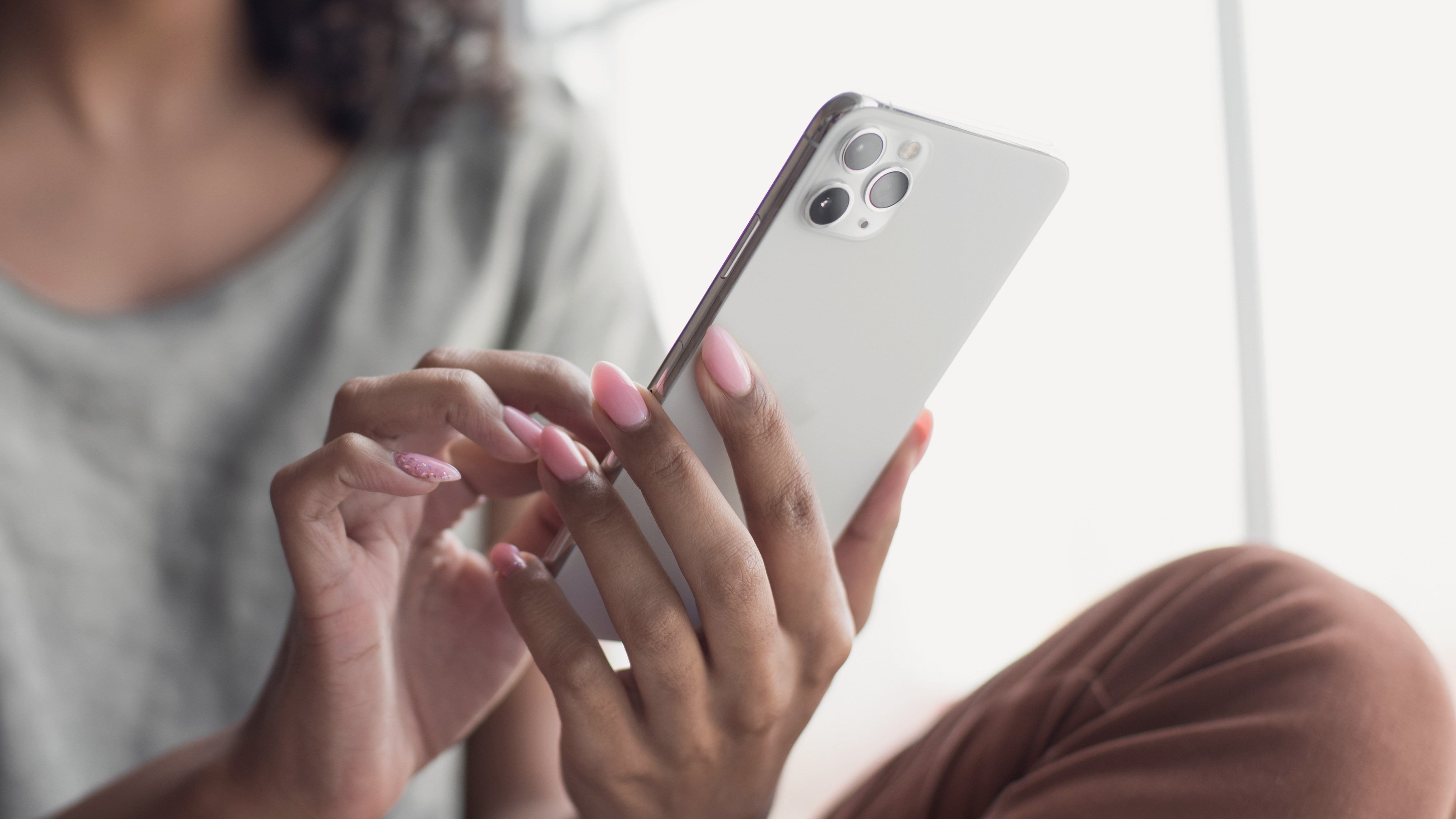 A person touching the screen of a white iPhone while holding it with the other hand.